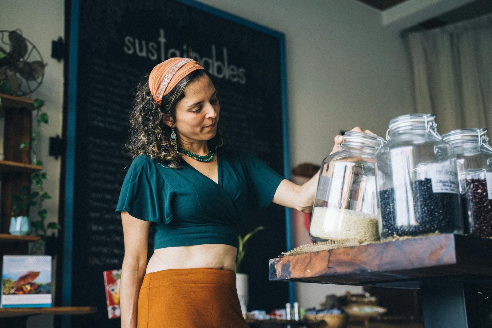 A Woman in Green Crop Top Looking at the Glass Jars on the Wooden Table